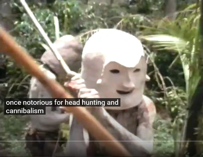Deux guerriers asaro portant leurs masques de boue performent au village de Komunive dans les Hautes Terres papoues. Le sous-titre indique qu'ils étaient connus pour la chasse de tête et le cannibalisme.