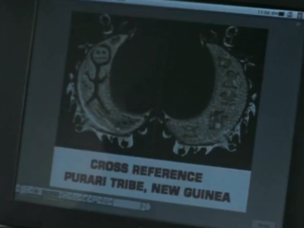 Un médaillon en forme de croissant portant des dessins indigènes apparaît sur l'écran de Ryan. La légende indique que cela renvoie à la tribu des Puraris de Nouvelle-Guinée.