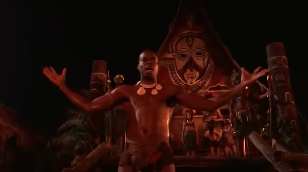 Le jeune guerrier papou Mudo (Demore Barnes) exulte la nuit devant la maison communale de son village.