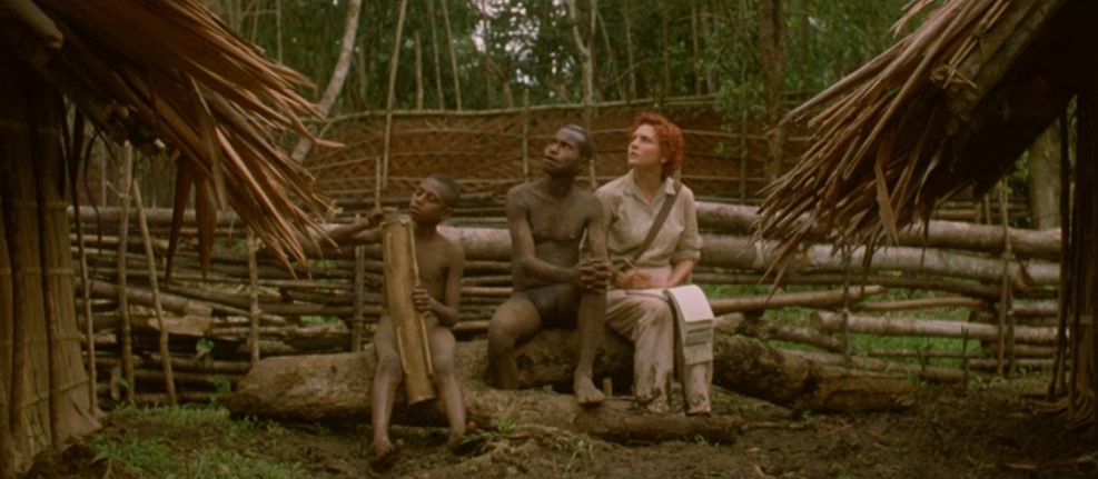 Dans un village, l'anthropologue Evelyn Spence (Maya Stange) et un Papou, assis, regardent au ciel l'approche des avions japonais, pendant qu'un enfant joue avec son tambour tubulaire.