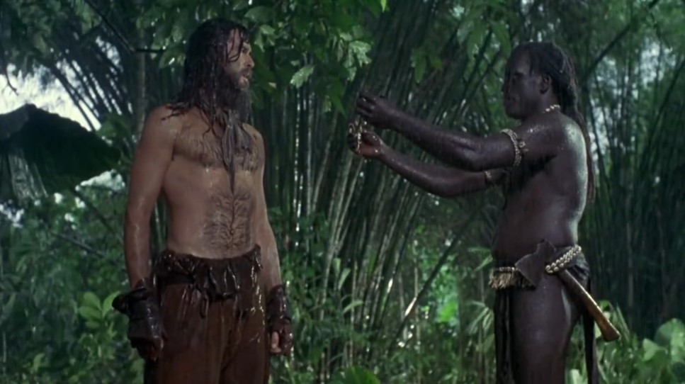 Robinson Crusoé (Pierce Brosnan) reçoit un collier de la part de Vendredi (William Takaku).