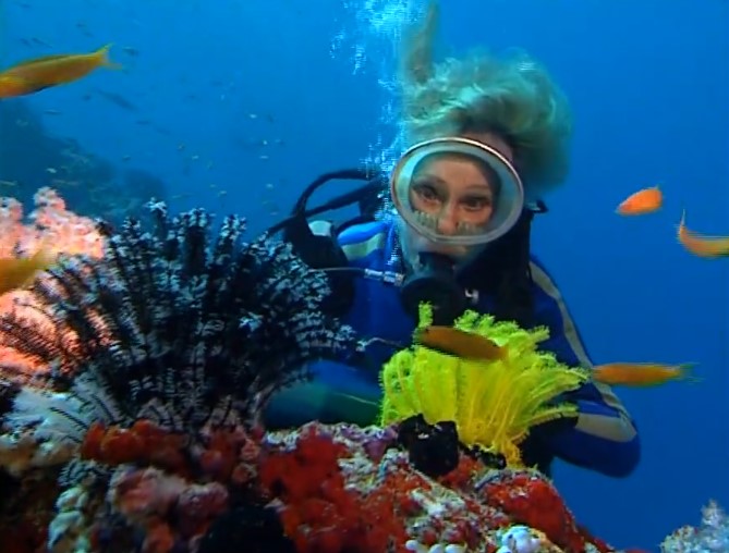 Leni Riefenstahl en tenue de plongée observe un récif corallien coloré.