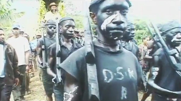Lors du sing-sing de Mount Hagen dans les hautes-terres de Papouasie-Nouvelle-Guinée, des jeunes défilent grimés en costume noir militaire devant le palanquin de l'ancien premier ministre Paias Wingti.