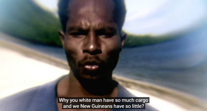 Le visage de Yali apparaît sur fond de plage, déclarant: "pourquoi vous les hommes blancs avez autant de cargaisons, et nous les Néo-Guinéens, si peu?"