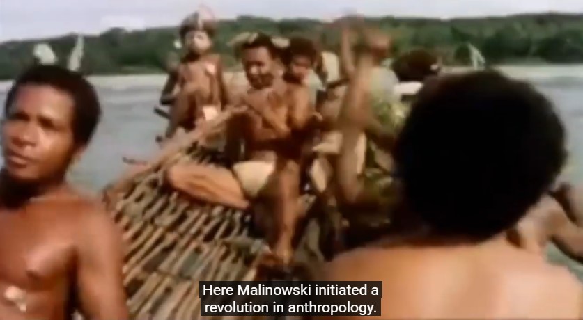 Un groupe d'habitants des îles Trobriand pagayent sur un grand canoë. La légende indique: "Malinowski a initié là-bas une révolution en anthropologie".