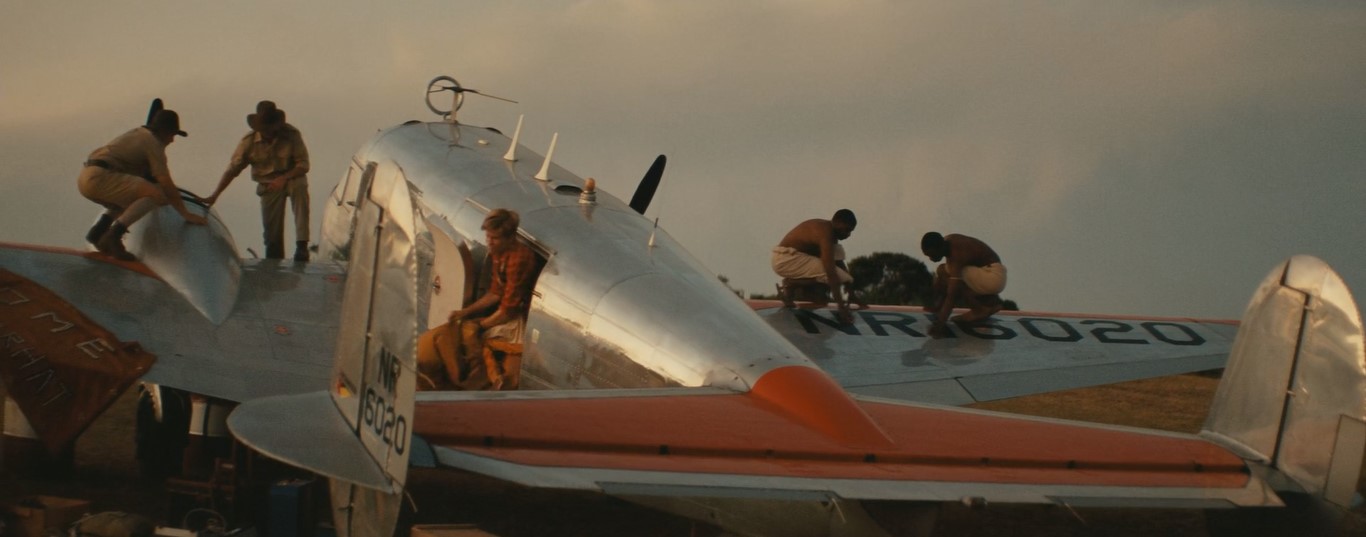Amelia Earhart (Hilary Swank) prépare son avion Electra sur la piste de Lae en Nouvelle-Guinée; des officiers australiens et des manutentionnaires papous l'aident.