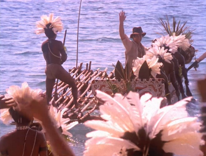 Le jeune Indiana Jones (Sean Patrick Flanery), embarqué sur un canoë décoré conduit par les Trobriandais, dit au-revoir de sa main droite.