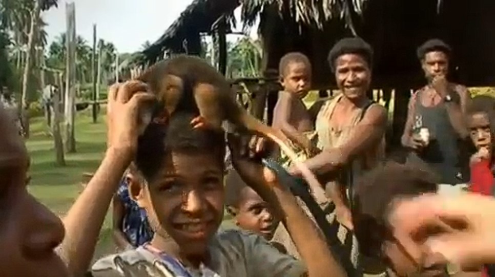Un enfant tient un marsupial couscous sur sa tête au milieu d'autres membres de la tribu Tayap du village de Gapun, à l'embouchure de la rivière Sépik de Papouasie-Nouvelle-Guinée.