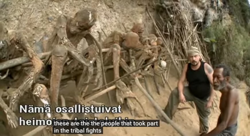 Riku Rantala et son guide papou Sam Ifid au cimetière des momies kukukuku d'Aseki; la légende indique que ce sont les guerriers qui prirent part dans les luttes tribales.