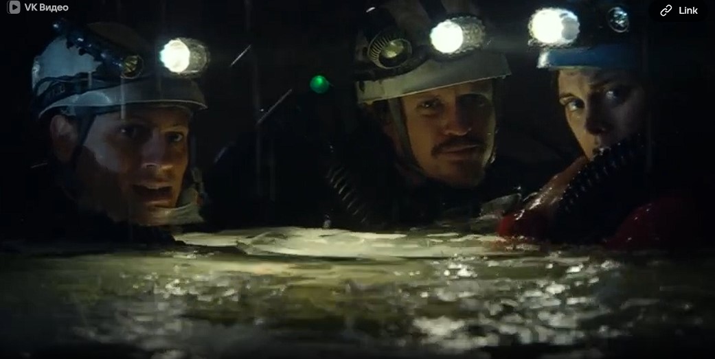 Les explorateurs Carl (Ioan Gruffudd), George (Dan Wyllie) et Vic (Alice Parkinson) examinent avec leurs lampes frontales un passage sous-terrain.